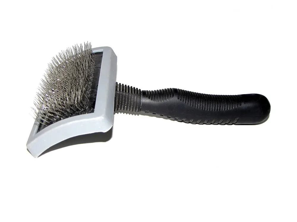 Slicker dog brush with a curved grey head of fine bent metal pins and a black ribbed handle